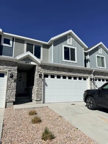 View of front of home featuring a garage, driveway, stone siding, and board and batten siding