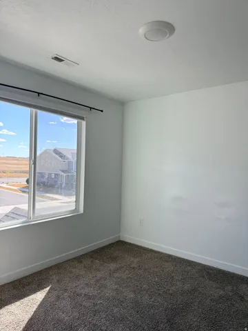 Spare room featuring baseboards and dark carpet