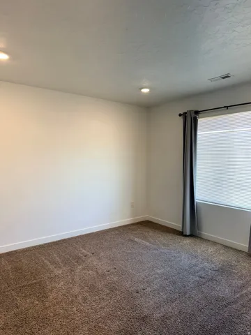 Spare room featuring baseboards and dark colored carpet