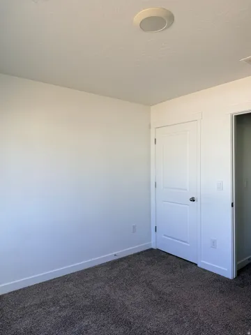 Unfurnished bedroom featuring dark carpet and a closet