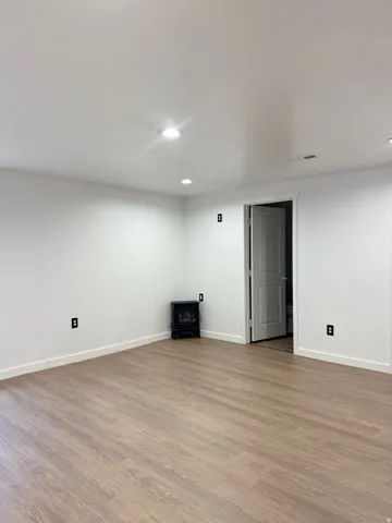 Finished below grade area featuring wood finished floors, recessed lighting, and a wood stove