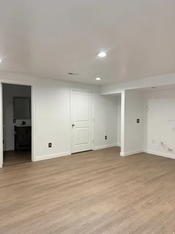 Finished basement with light wood-type flooring and recessed lighting
