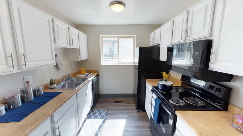 Kitchen featuring black appliances, white cabinets, light countertops, and dark wood-type flooring