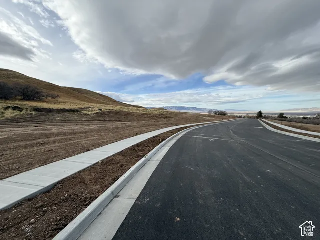 View of asphalt road featuring a mountain view and curbs