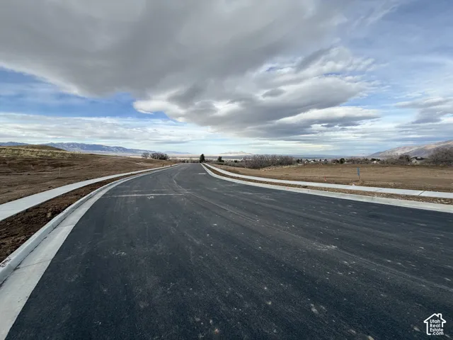 View of asphalt street featuring a mountain view, sidewalks, and curbs
