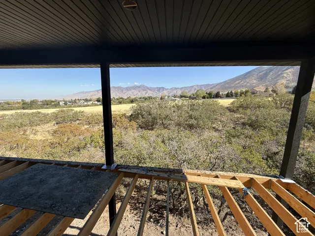 Covered outdoor structure with exposed wood framing, supported by dark structural posts, offering expansive mountain scenery