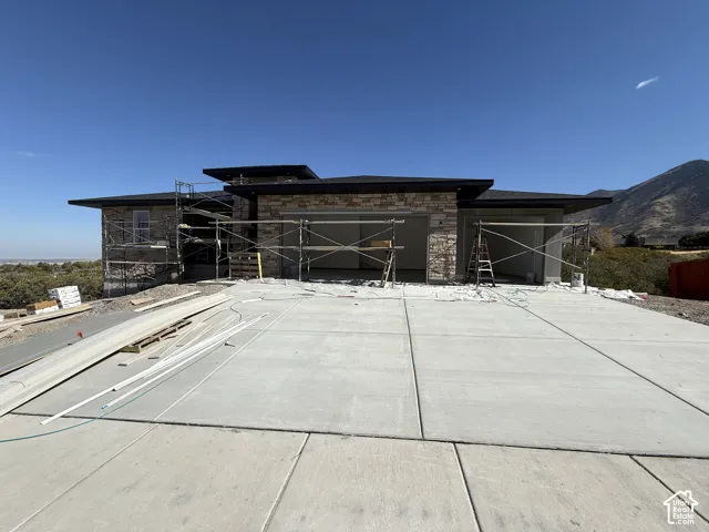 Stone veneer exterior with a concrete driveway and mountain backdrop