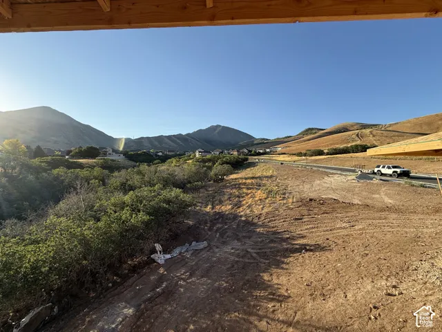 Expansive property with natural vegetation, framed by distant mountains and rolling hills