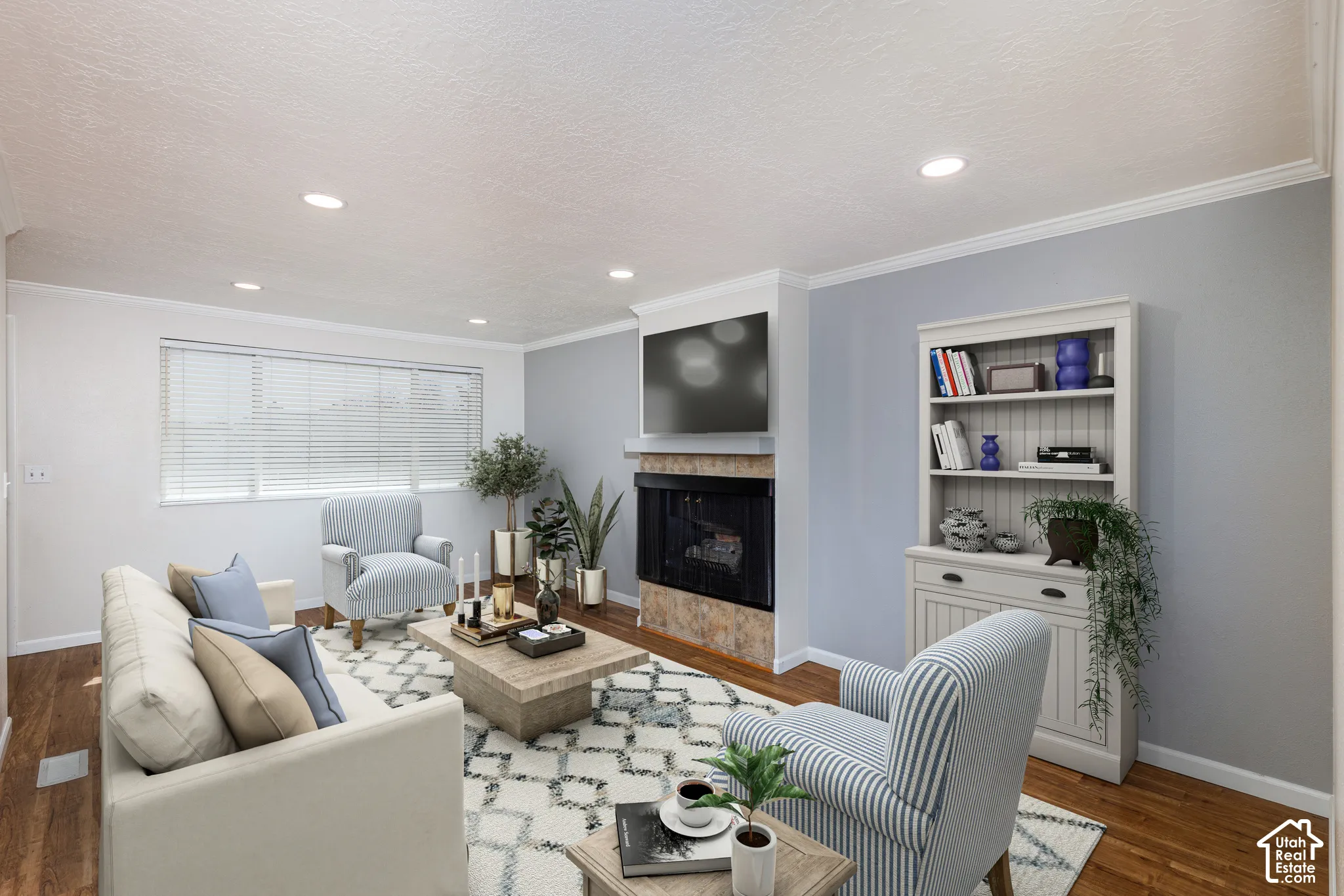 Recessed lighting, wood-finish flooring, corner fireplace with stone surround and mantel, built-in shelving, and crown molding