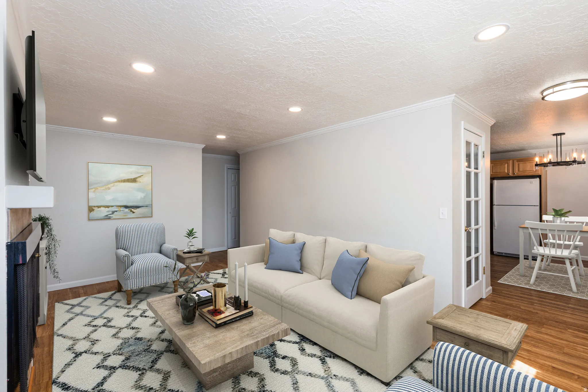 Recessed lighting, crown molding, wood-finish flooring, white walls, and a fireplace with a white mantel
