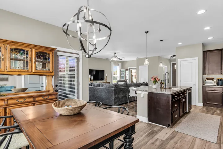 Open-concept living space with wood-finish flooring, a kitchen island with stone countertop, and pendant lighting