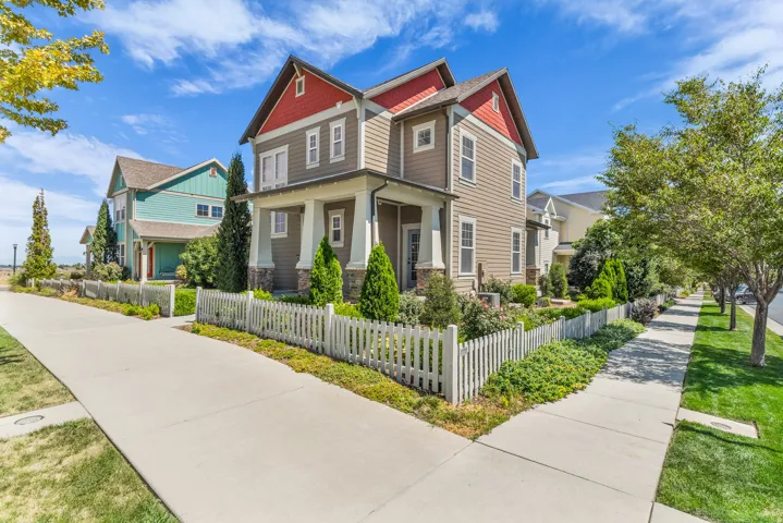 Two-story residence featuring composite siding, a covered front porch with substantial columns, and a white picket fence