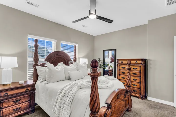 Dual windows with blinds, ceiling fan, and neutral wall paint