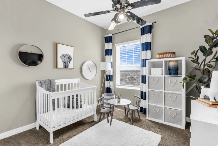 Neutral wall paint, ceiling fan, window with blinds, and white built-in shelving unit