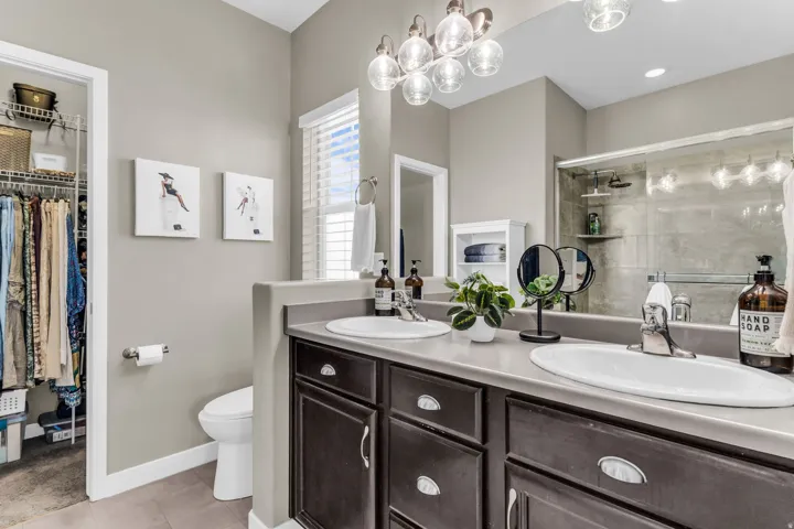 Dual basin vanity with dark wood-finish cabinetry, chrome fixtures, and a large wall-mounted mirror