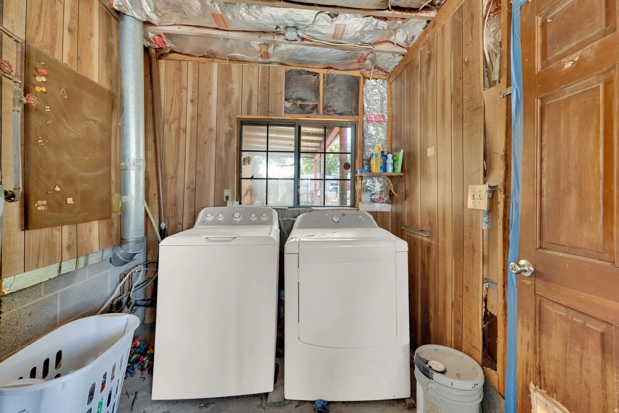 Laundry area featuring wood walls and independent washer and dryer