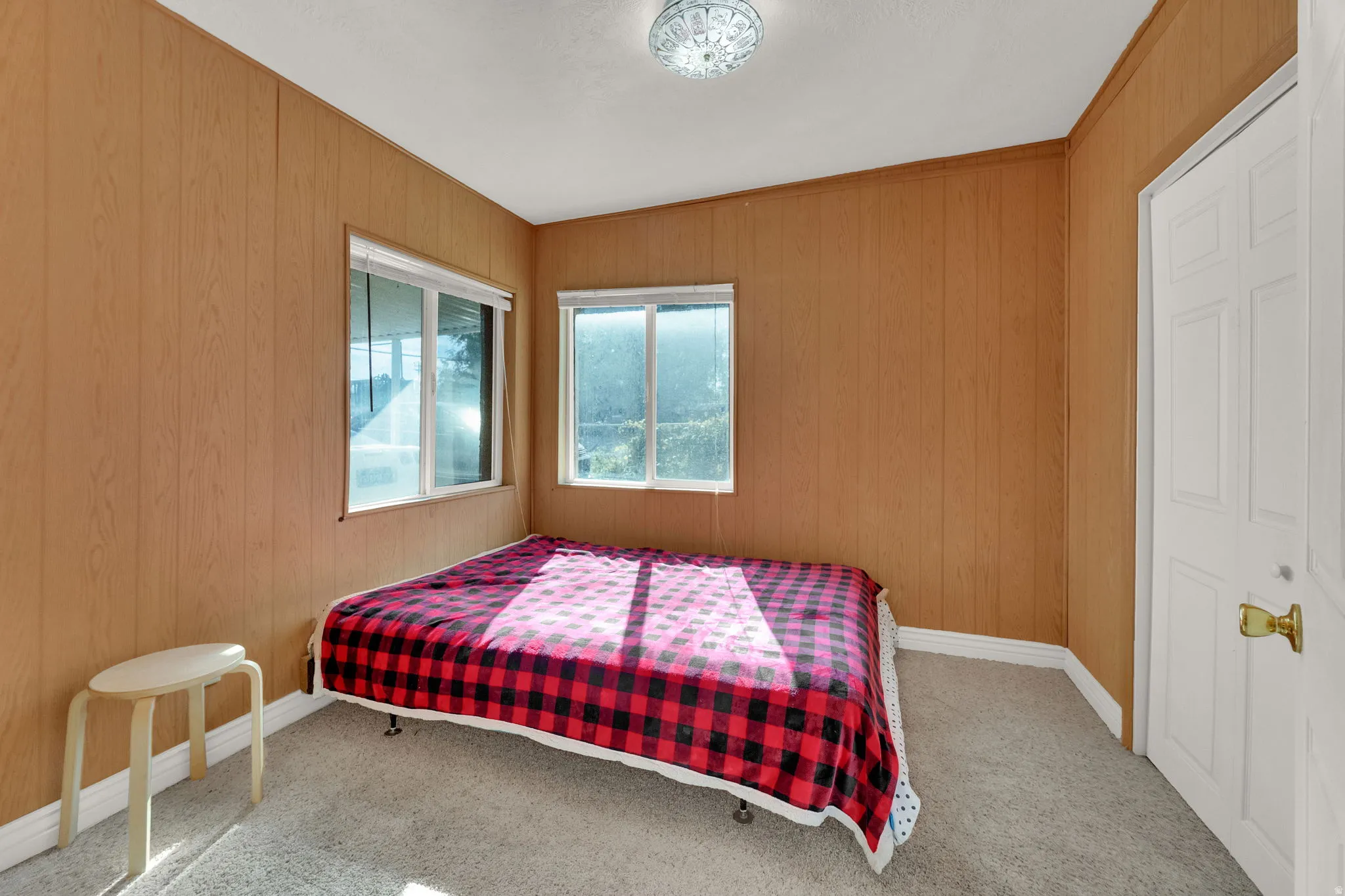 Bedroom with light carpet and wooden walls