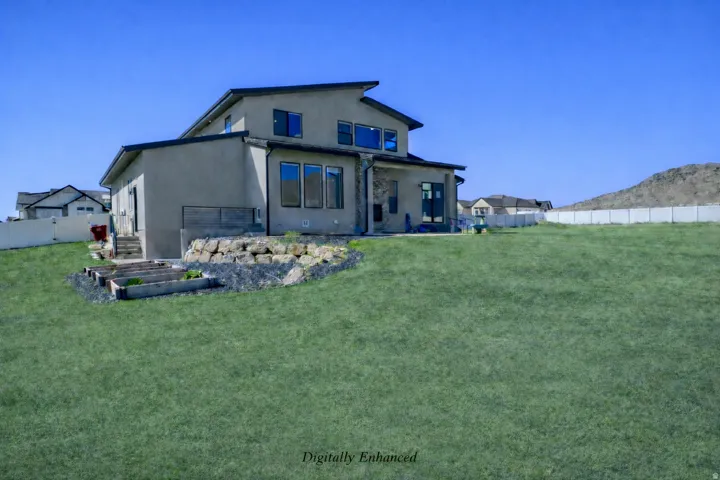 Back of property featuring a fenced backyard, stucco siding, a mountain view, and a garden