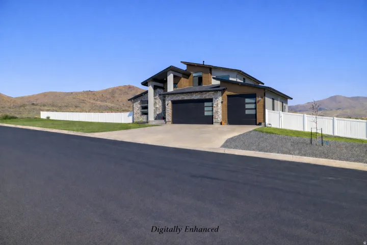 Contemporary home featuring a mountain view, stone siding, an attached garage, and driveway
