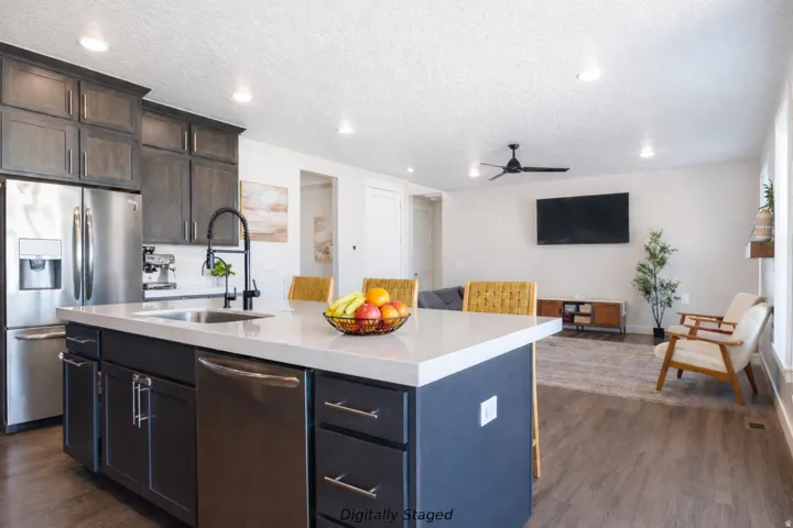 Kitchen with stainless steel appliances, open floor plan, dark wood finished floors, a textured ceiling, and light stone countertops
