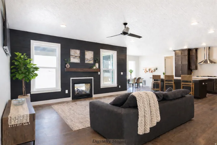 Living room with a textured ceiling, ceiling fan, recessed lighting, dark wood-style flooring, and a multi sided fireplace