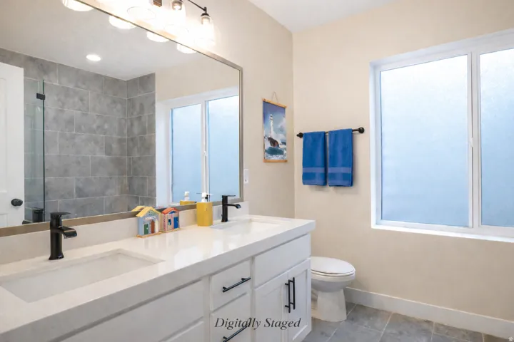 Bathroom with double vanity, light tile patterned floors, and a shower