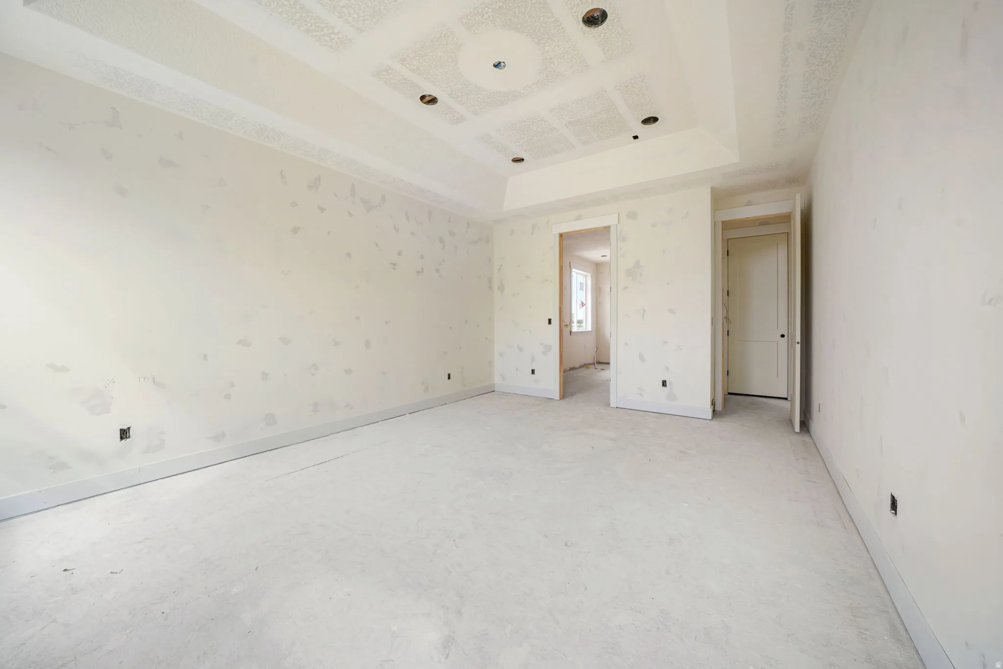 Unfurnished bedroom featuring wallpapered walls and a tray ceiling