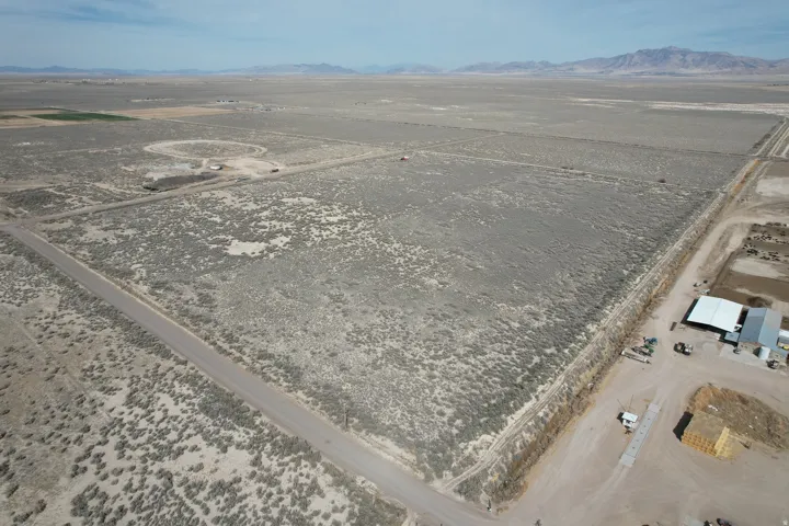 Aerial view of property and surrounding area featuring rural landscape and a mountain backdrop