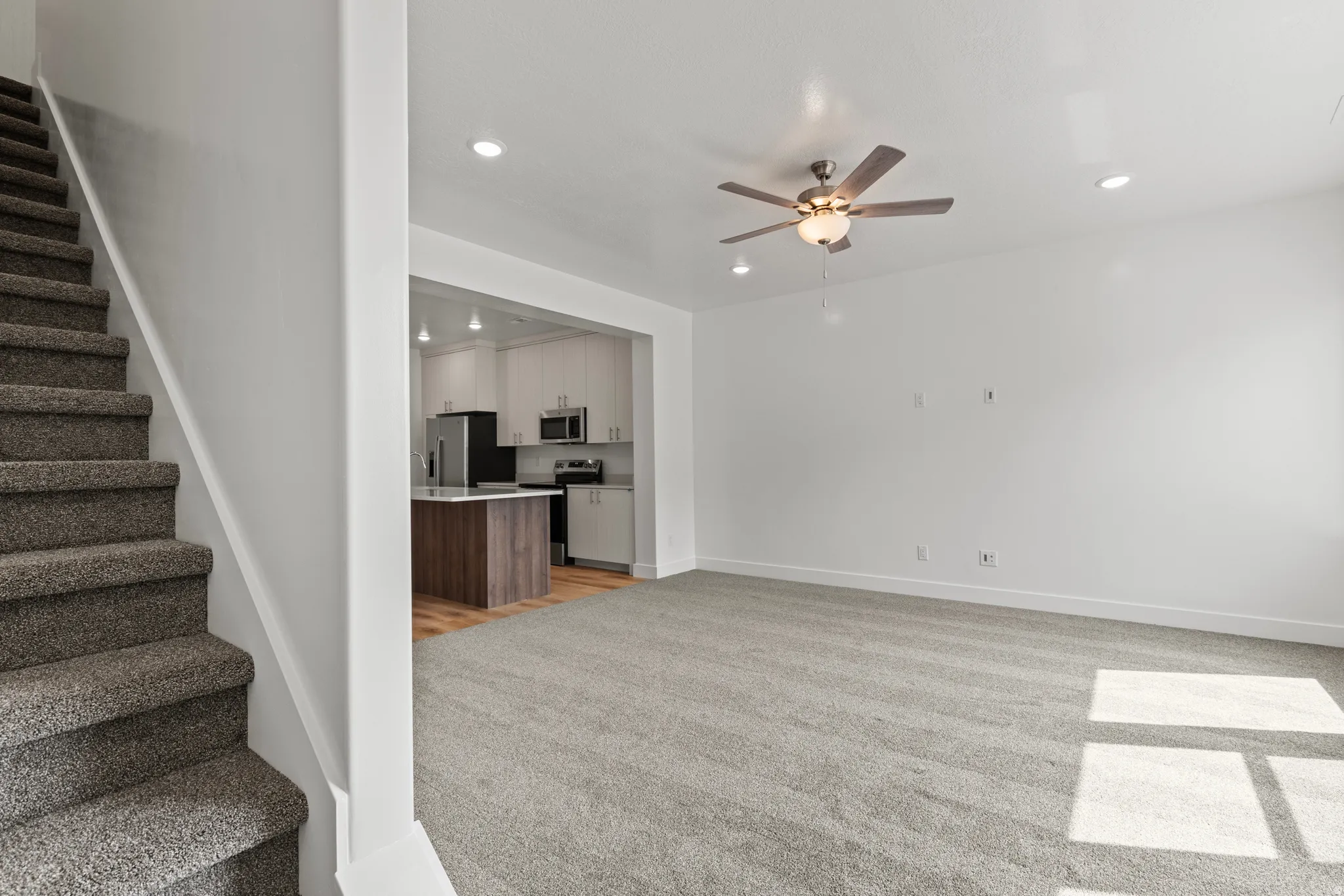 Unfurnished living room featuring a ceiling fan, recessed lighting, and light carpet