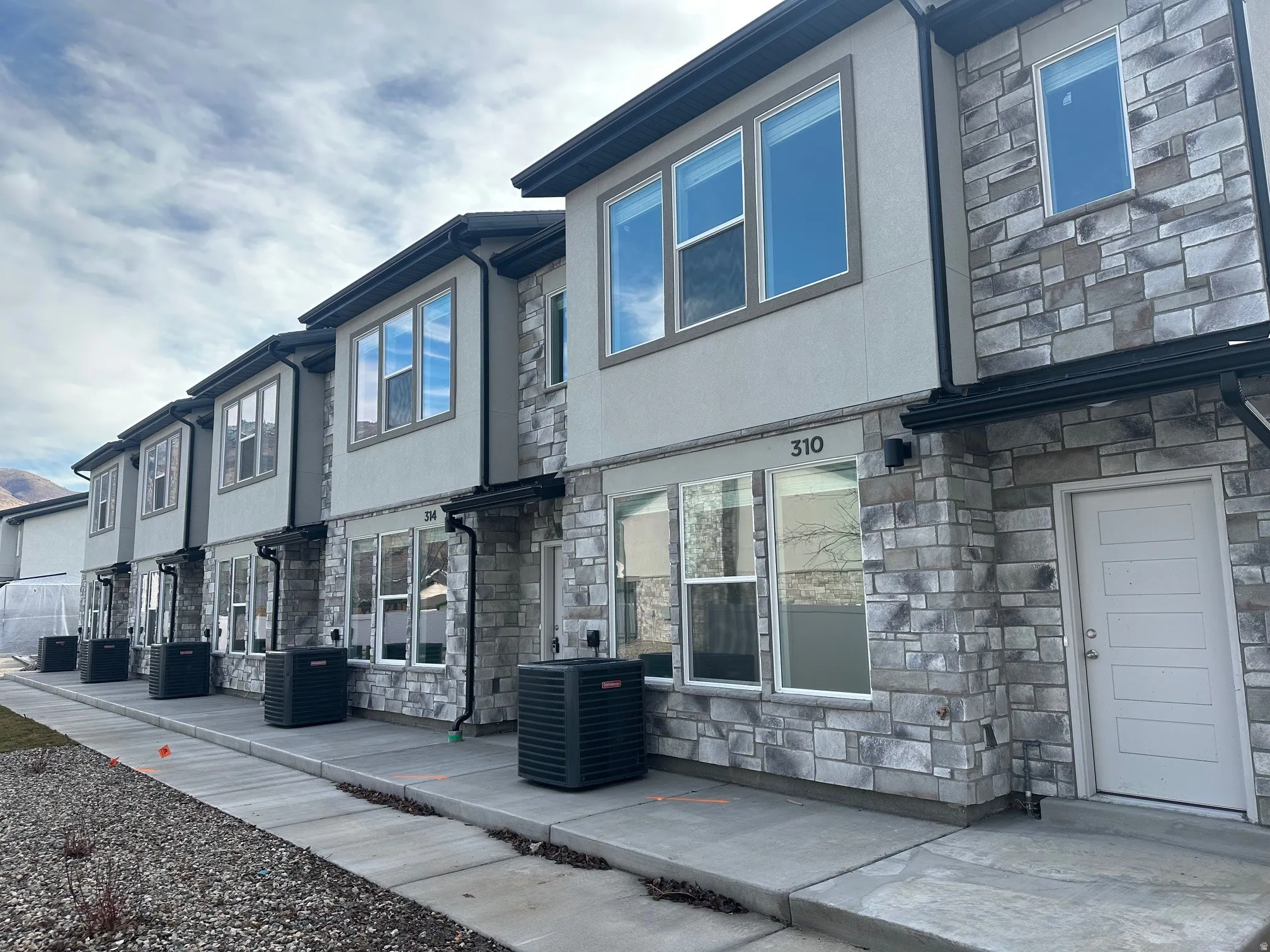 Back of house featuring stone siding and stucco siding