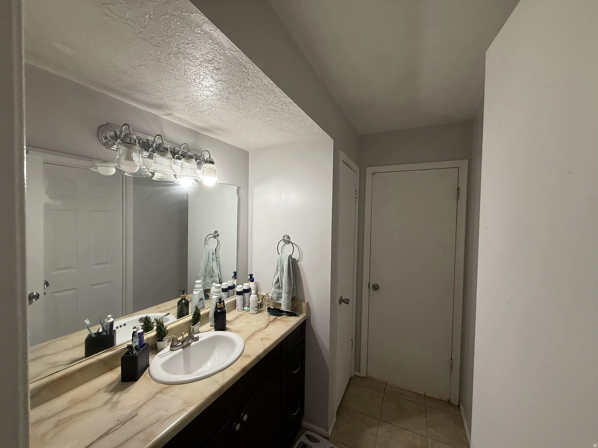 Bathroom featuring vanity, a textured ceiling, and light tile patterned flooring