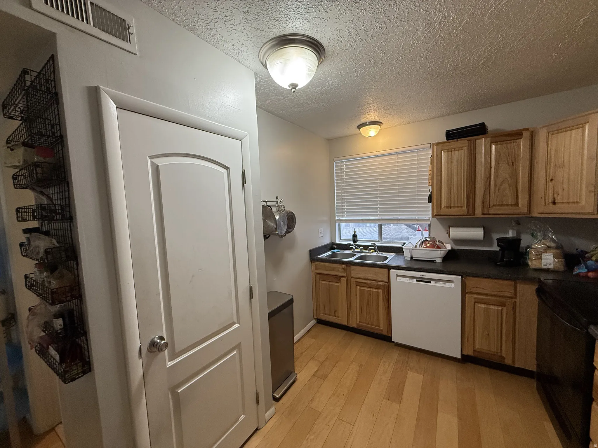 Kitchen featuring dishwasher, dark countertops, light wood-type flooring, and black range with electric cooktop