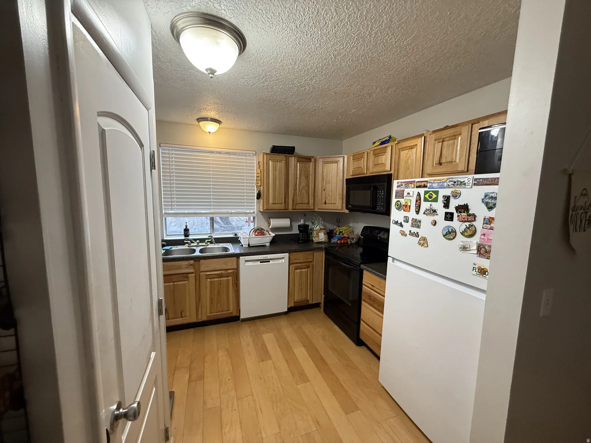 Kitchen featuring black appliances, dark countertops and light wood finished floors