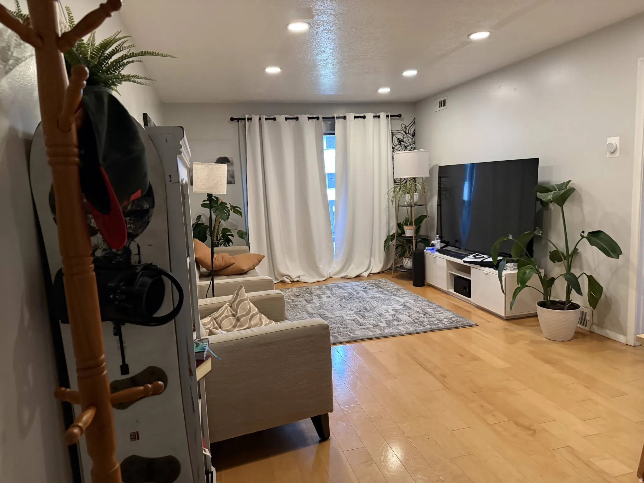 Living room with light wood-type flooring and recessed lighting