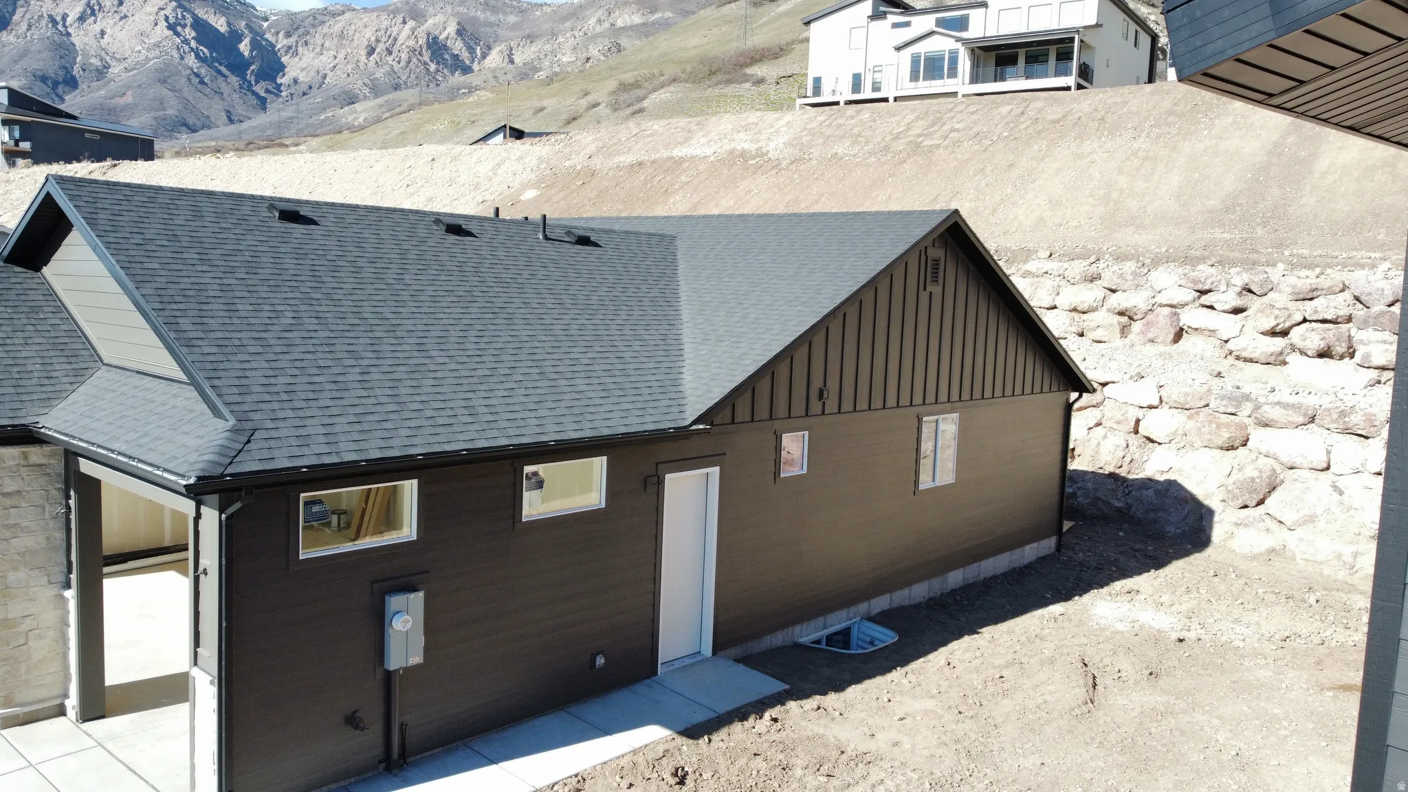View of home's exterior with a shingled roof, a mountain view, and board and batten siding