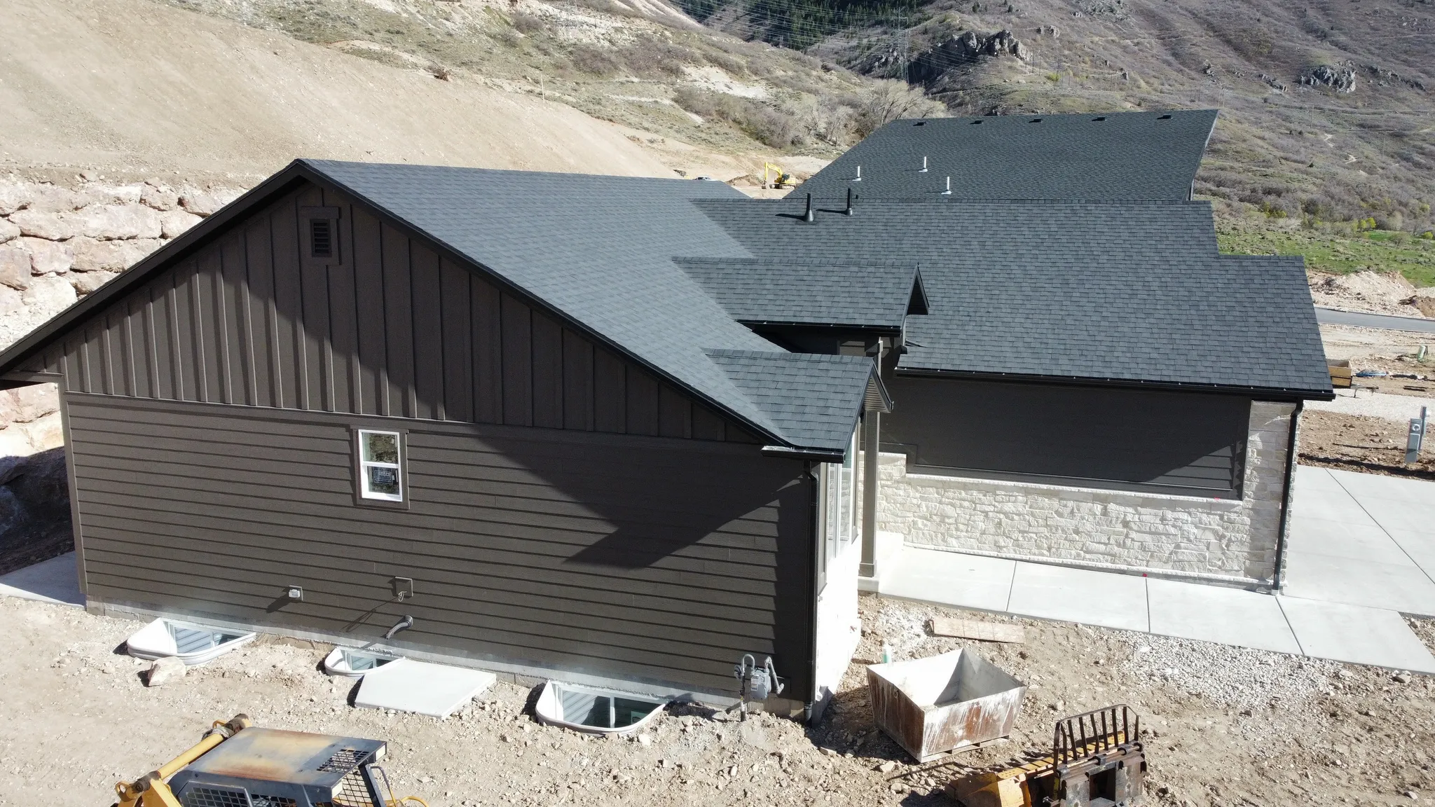 View of property exterior with roof with shingles, board and batten siding, a mountain view, and stone siding