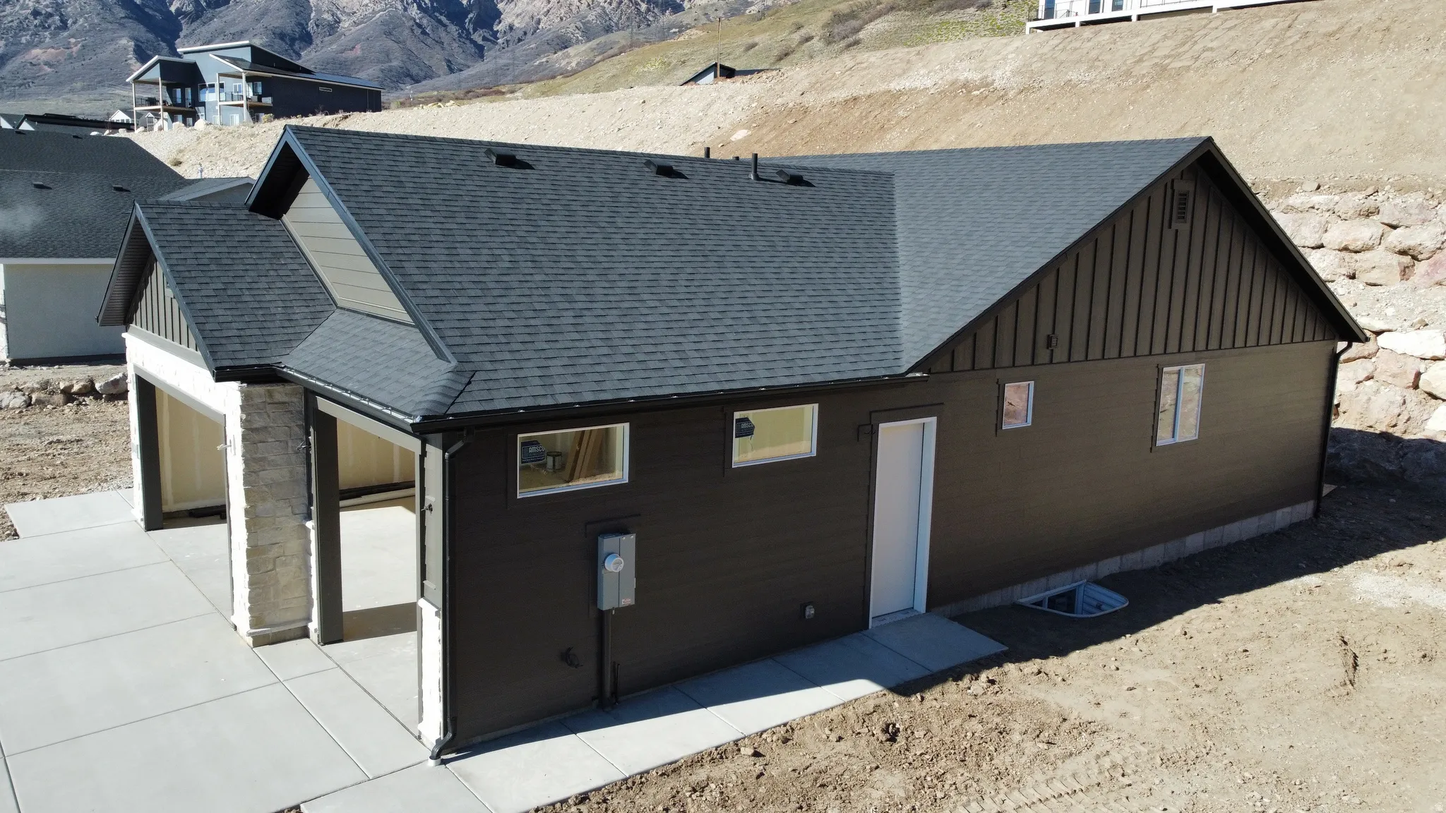 View of side of property featuring a shingled roof, board and batten siding, a mountain view, and stone siding