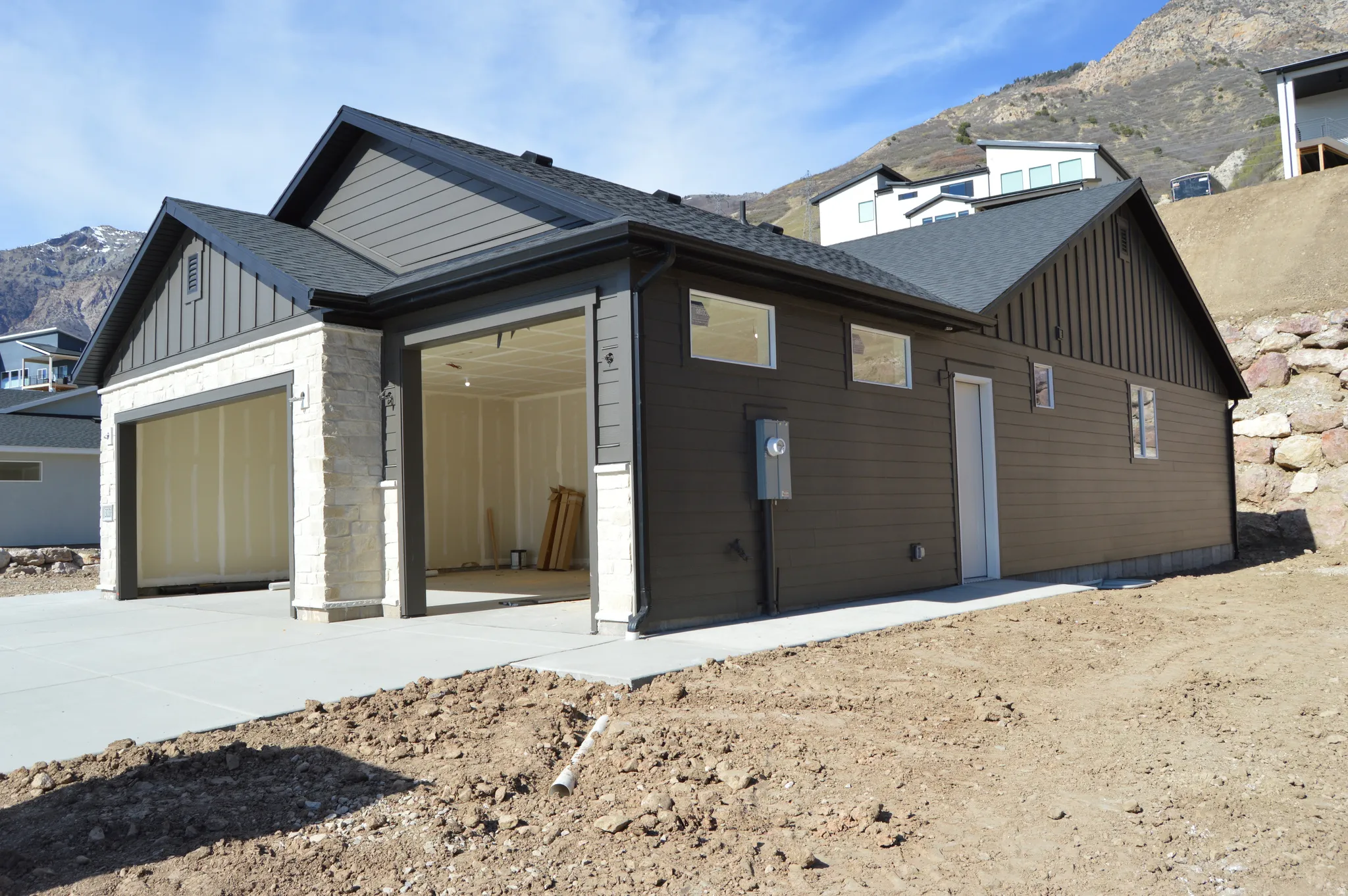 View of property exterior with board and batten siding, a mountain view, roof with shingles, and stone siding