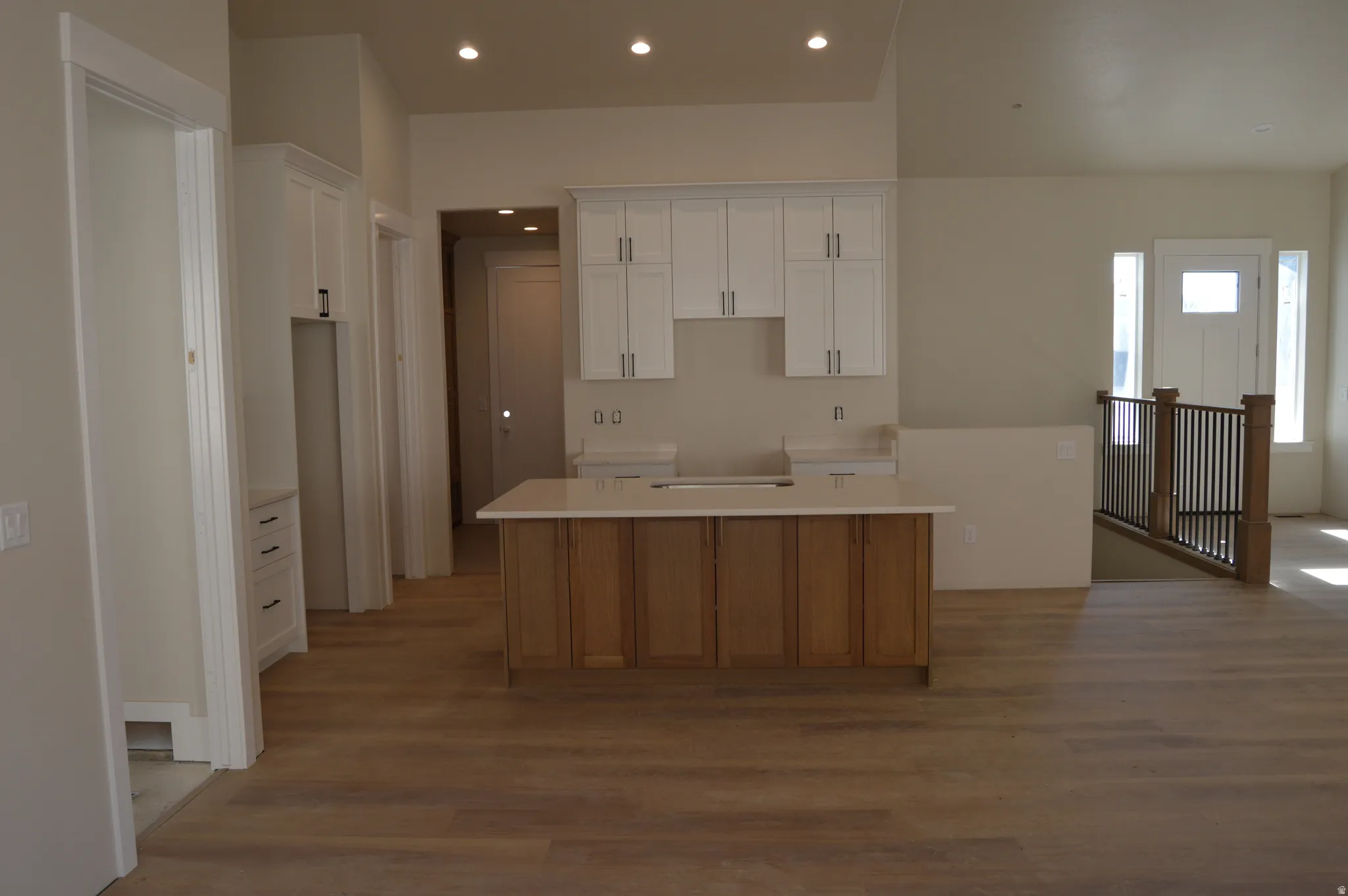 Kitchen featuring a kitchen island, two tone cabinets, recessed lighting, and wood finished floors