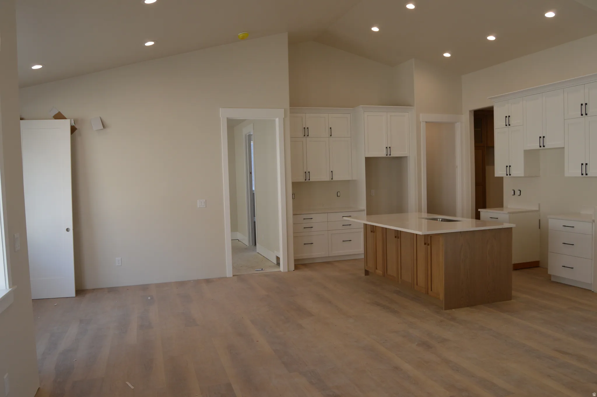 Kitchen featuring two tone color scheme, a center island with sink, recessed lighting, and light wood finished floors