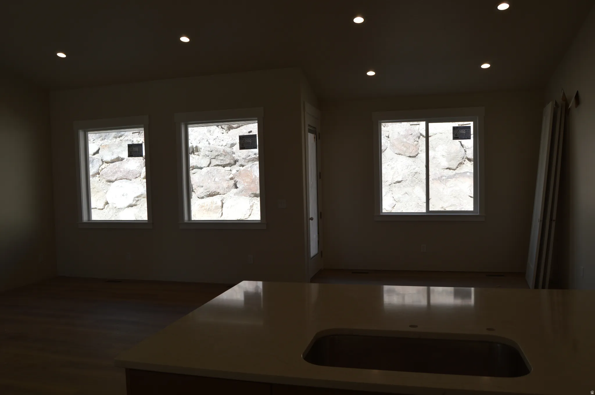 Kitchen featuring recessed lighting, healthy amount of natural light, light stone countertops, and dark wood-style flooring