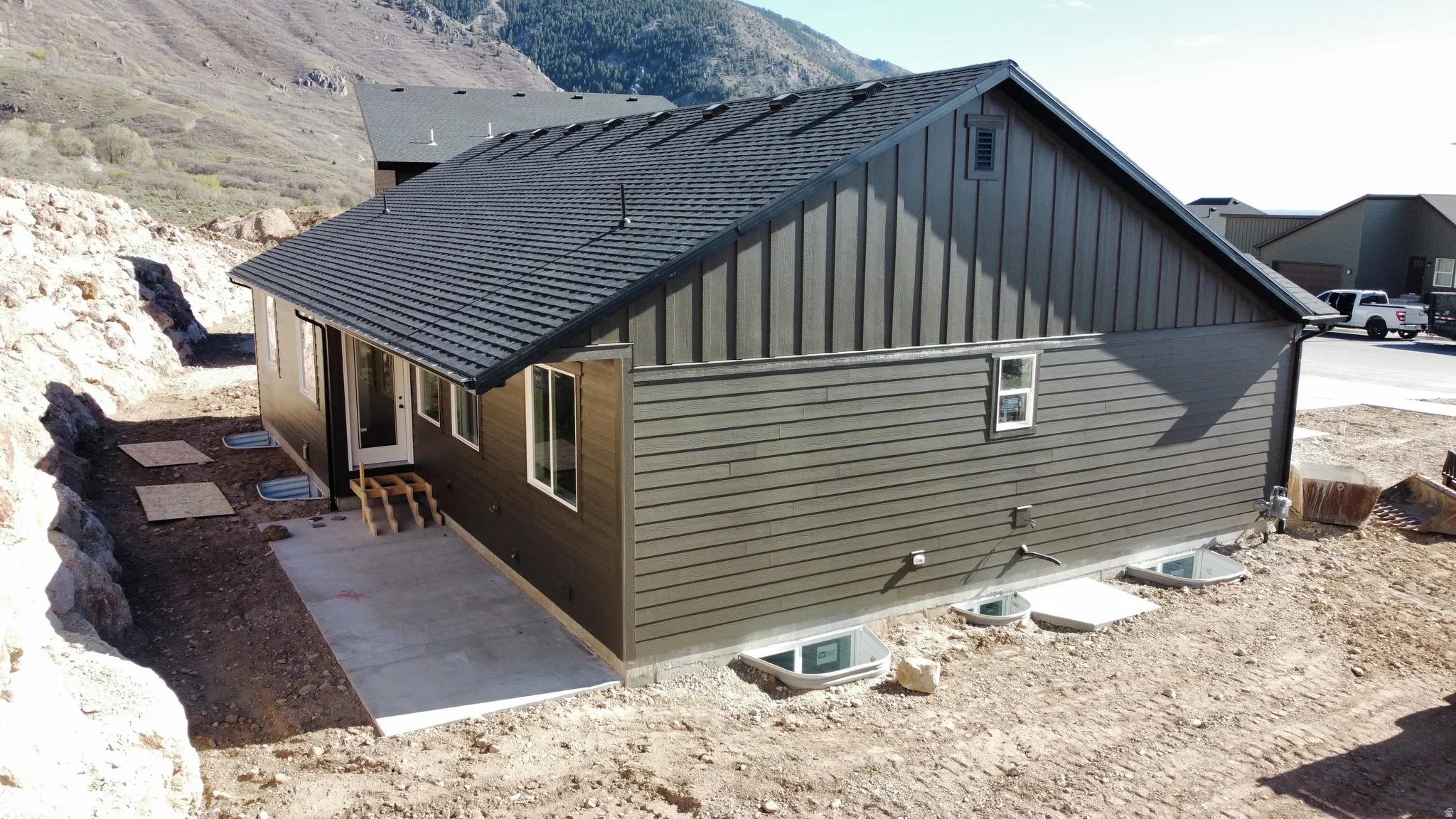 View of side of home with board and batten siding, a mountain view, and a patio
