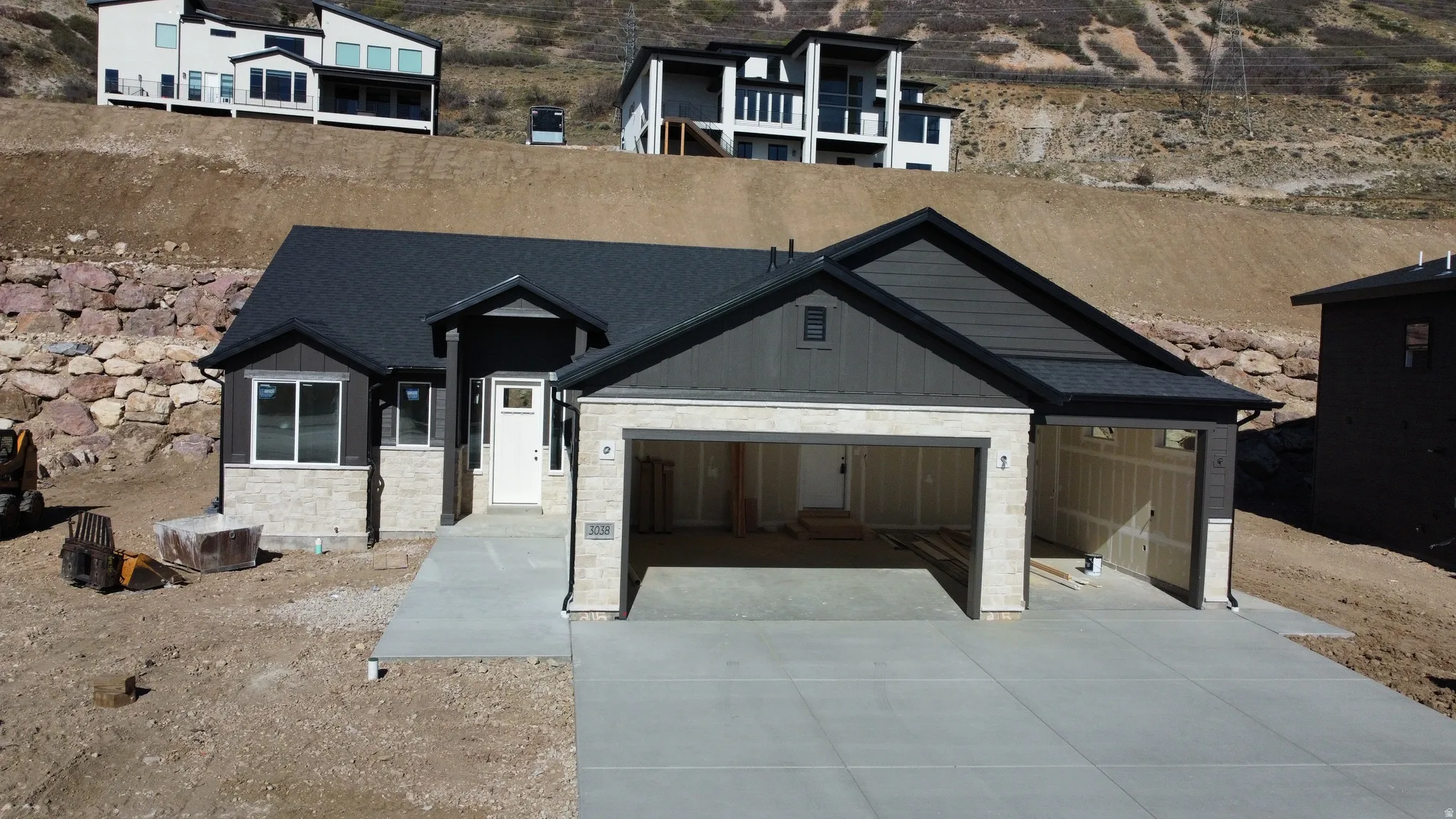 Contemporary home with an attached garage, driveway, and stone siding
