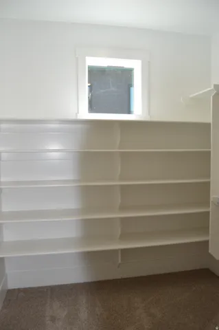 Built-in shelving units, window with white trim, and neutral-toned carpeting