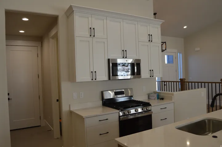 White shaker-style cabinetry with matte black hardware, stainless steel appliances, and light-toned countertops