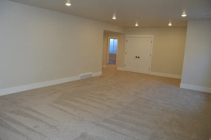 Plush carpet flooring, recessed ceiling lighting, light neutral wall paint, white trim, and white double doors with black hardware