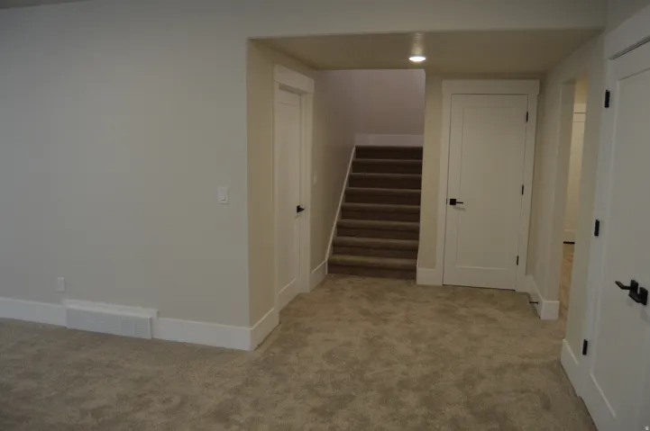 Carpeted flooring extending to stairs, white interior doors, and recessed lighting