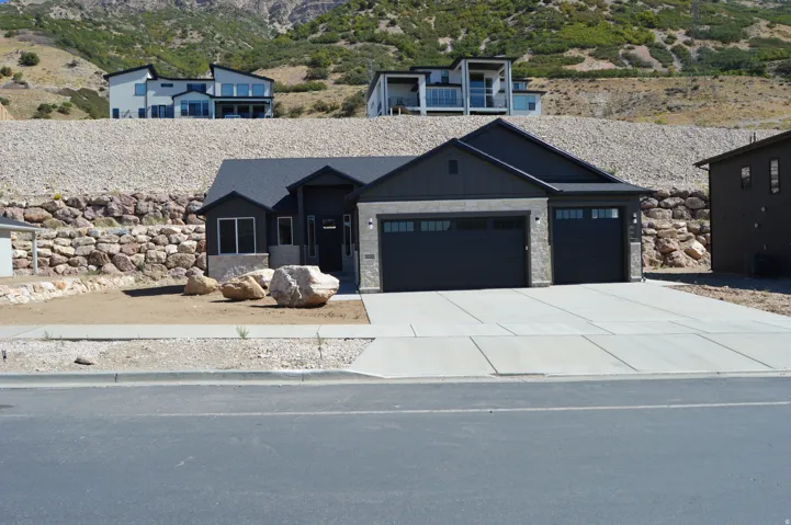 Contemporary-style residence featuring a dark gray facade with vertical siding accents, an attached two-car garage, and a concrete driveway