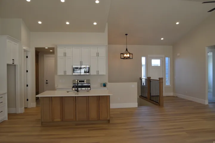 Open-concept living space with wood-finish flooring, vaulted ceilings, and recessed lighting