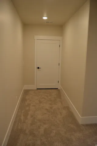 Recessed ceiling lighting, neutral carpet, flat-panel interior door, and dark door hardware